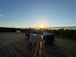a group of chairs sitting on a deck with the sunset at LUNA Self Check-in Hotel Klaipeda in Klaipėda