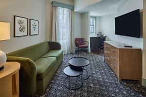 a living room with a green couch and a television at The Partridge Inn Augusta, Curio Collection by Hilton in Augusta