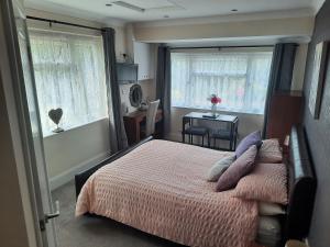 a bedroom with a bed and two windows and a table at Greenlands Guest House in Highbridge
