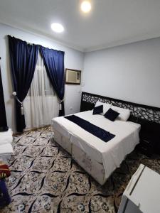 a bedroom with a large bed with blue curtains at Najmat Alnoor Almaabdah Hotel in Makkah