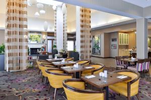 ein Restaurant mit Holztischen und gelben Stühlen in der Unterkunft Hilton Garden Inn Hobbs in Hobbs