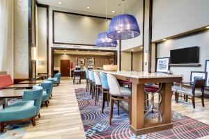 a hotel lobby with a bar and chairs at Hampton Inn & Suites Greenville Airport in Greenville