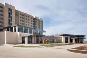 a large office building with a sculpture in front of it at Embassy Suites by Hilton Kansas City Olathe in Olathe