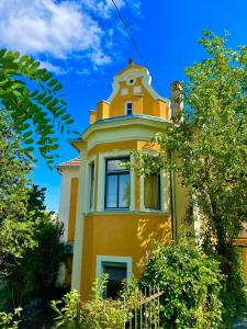 un edificio amarillo con una torre encima en Villa Luca en Mosonmagyaróvár