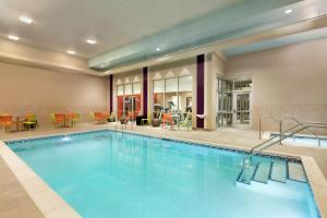 a pool in a hotel with tables and chairs at Home2 Suites by Hilton Minneapolis Bloomington in Bloomington