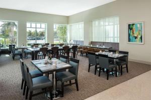 a dining room with tables and chairs and windows at Hilton Garden Inn Miami Dolphin Mall in Miami