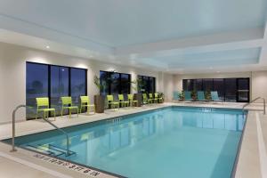 a pool in a hotel with chairs and tables at Home2 Suites by Hilton Milton Ontario in Milton