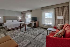 Hampton Inn & Suites Artesia في أرتيشيا: غرفه فندقيه بسرير واريكه
