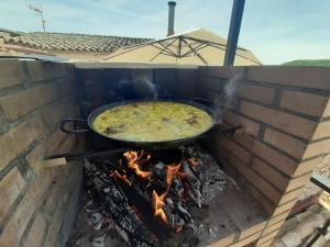una gran olla de comida cocinando sobre un fuego en Ático Rural en pareja, amigos o familia a la montaña "EL COLMENAR", en Chóvar