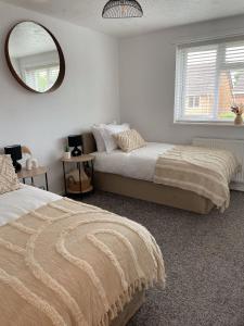 a bedroom with two beds and a mirror at Cosy & stylish home from home in Peterborough