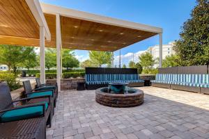 acovered patio with blue chairs and a fire pit at Home2 Suites by Hilton Orlando International Drive South in Orlando