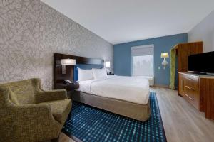 オーランドにあるHome2 Suites by Hilton Orlando International Drive Southのベッド、椅子、テレビが備わるホテルルームです。