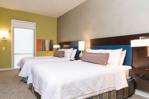 インディアナポリスにあるHome2 Suites by Hilton Indianapolis Downtownのベッド2台と窓が備わるホテルルームです。