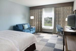 um quarto de hotel com uma cama, um sofá e uma televisão em Hampton Inn & Suites Stillwater West em Stillwater