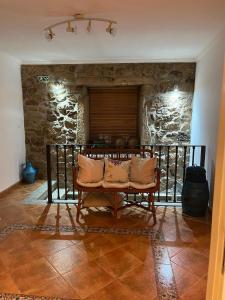 a living room with a bench and a stone wall at Benedita's House in Capinha