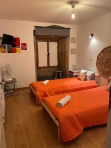 two beds in a room with orange sheets at Benedita's House in Capinha