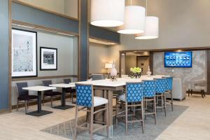 a dining room with tables and chairs and a tv at Hampton Inn and Suites Michigan City in Michigan City