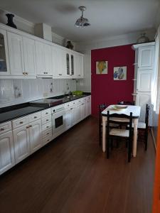 a kitchen with white cabinets and a table in it at Hostal Quiper in Quiroga