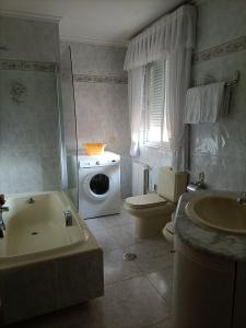 a bathroom with a toilet and a washing machine in it at Hostal Quiper in Quiroga