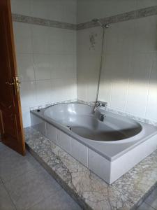 a large bath tub in a bathroom with marble tiles at Hostal Quiper in Quiroga