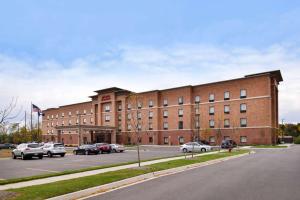 un grand bâtiment en briques avec des voitures garées dans un parking dans l'établissement Hampton Inn & Suites Ann Arbor West, à Ann Arbor