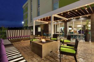 西门罗Home2 Suites by Hilton West Monroe的一个有火坑和椅子的露台和一栋建筑
