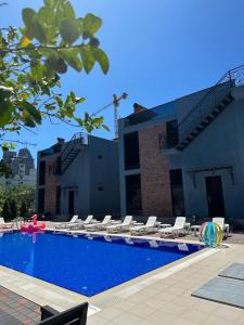 a swimming pool with chaise lounges and chairs next to a building at Villa Residence in Kvariati