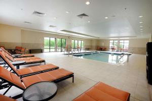 a swimming pool in a large room with tables and chairs at Hampton Inn & Suites Ponca City in Ponca City