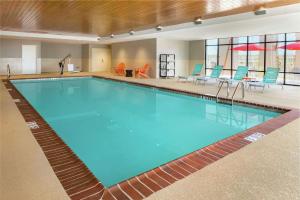 a swimming pool in a hotel room with blue chairs and tables at Home2 Suites by Hilton Alexandria in Alexandria