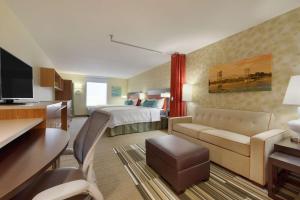 Habitación de hotel con cama y sala de estar. en Home2 Suites by Hilton Alexandria en Alexandria