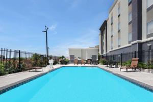 a swimming pool with chairs and a building at Hampton Inn & Suites San Antonio Brooks City Base, TX in San Antonio