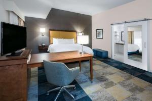 um quarto de hotel com uma cama e uma secretária com uma televisão em Hampton Inn & Suites San Antonio Brooks City Base, TX em San Antonio