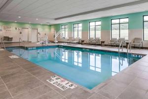 una piscina en un gimnasio con mesas y sillas en Hampton Inn & Suites-Hudson Wisconsin, en Hudson