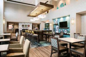 a restaurant with tables and chairs and a bar at Hampton Inn & Suites-Hudson Wisconsin in Hudson