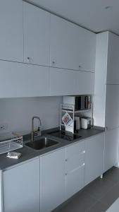 a kitchen with white cabinets and a sink at Seafront rooftop flat w/ terrace in Portovenere