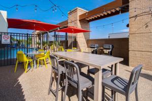 einen Holztisch mit Stühlen und Sonnenschirmen auf einer Terrasse in der Unterkunft Home2 Suites By Hilton Waco in Waco