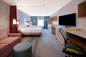 ウェイコにあるHome2 Suites By Hilton Wacoのベッドとテレビが備わるホテルルームです。