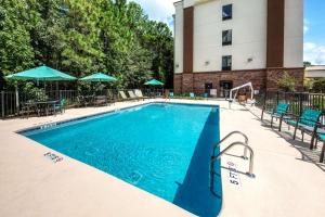 a swimming pool with tables and chairs and a building at Hampton Inn Summerville SC in Summerville