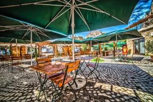 un patio con mesas, sillas y sombrillas en DoubleTree by Hilton Hotel Sighisoara - Cavaler, en Sighişoara