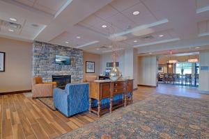 Hampton Inn & Suites Cazenovia, NY في Cazenovia: لوبي به موقد حجري وكراسي زرقاء