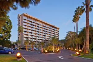 ein großes Gebäude auf einem Parkplatz mit Palmen in der Unterkunft Hotel La Jolla, Curio Collection by Hilton in San Diego