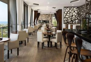 a restaurant with tables and chairs and windows at Hotel La Jolla, Curio Collection by Hilton in San Diego