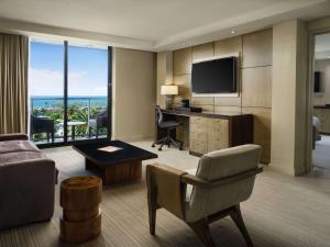 a living room with a couch and a desk with a television at Hotel La Jolla, Curio Collection by Hilton in San Diego