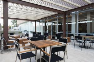 um restaurante com mesas e cadeiras de madeira e janelas em Hampton Inn by Hilton Irapuato em Irapuato