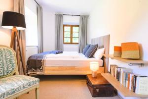 een slaapkamer met een bed en een stoel en een boekenplank bij Mountain Chalet on Gut Buchwies in Oberau