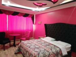 a pink bedroom with a bed and a pink wall at Hostal Kapital II in Quito