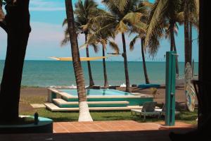 uma piscina junto à praia com palmeiras em Lali Beach Hotel Boutique em Sonsonate