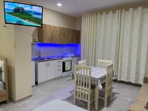 een keuken met een tafel en een tv aan de muur bij Ledio guest house in Pogradec