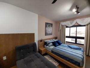 een slaapkamer met een bed, een stoel en een raam bij Lindo Apartamento na Frei Caneca in Sao Paulo