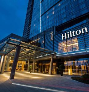 Hilton Wuhan Yangtze Riverside في ووهان: مبنى عليه علامة الهيلتون